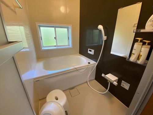 a bathroom with a tub and a toilet and a window at かげやんのいえ　KAGEYAN NO IE in Tsu