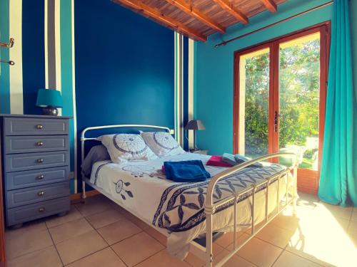 a bedroom with a bed with blue walls and a window at Gites Le Pagus in Simeyrols
