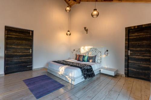 a bedroom with a bed in a room with wooden floors at Vibhasa-The Scenic Solitude Villa Amidst Himalayas Near Kainchi Dham-Where BBQ and Bonfires Ignite the Adventure in Rāmgarh