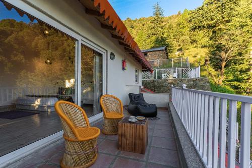 a patio with two chairs and a table on a balcony at Vibhasa-The Scenic Solitude Villa Amidst Himalayas Near Kainchi Dham-Where BBQ and Bonfires Ignite the Adventure in Rāmgarh