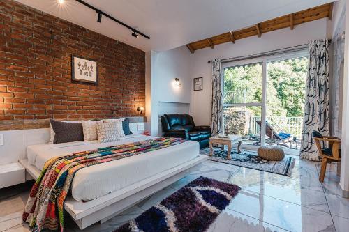 a bedroom with a bed and a brick wall at Vibhasa-The Scenic Solitude Villa Amidst Himalayas Near Kainchi Dham-Where BBQ and Bonfires Ignite the Adventure in Rāmgarh
