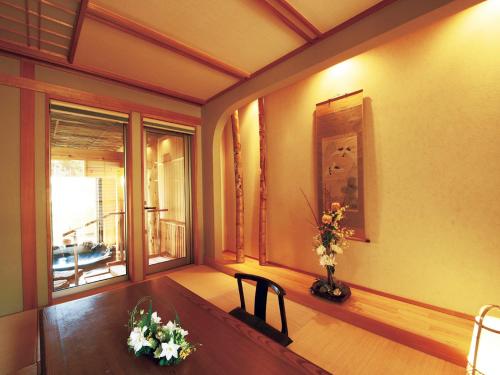 a room with a table and a window with flowers on it at Bettei Soan in Minami Aso