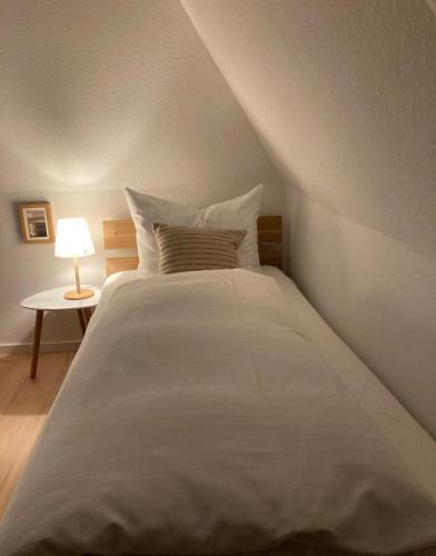 a large white bed in a room with a lamp at Strandkoje in Nebel