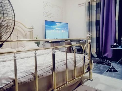 a metal bed in a room with a tv at serene luxury master bedroom in Sharjah
