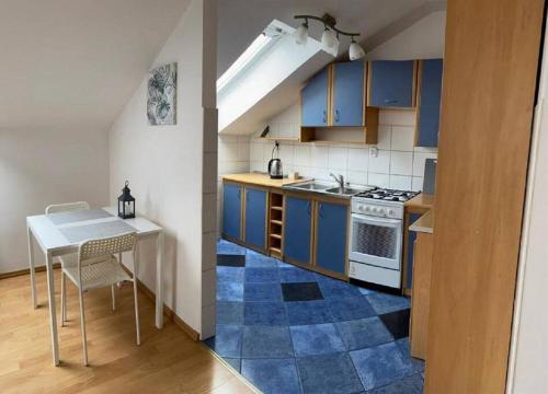 eine Küche mit blauen Schränken, einem Tisch und einem Herd in der Unterkunft Apartament NOWY in Ostrowo