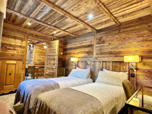 two beds in a room with wooden walls at Chalet Les Cocales Résidence Séjour et nuitées B&B - Appartement Pin Cembro in Bessans