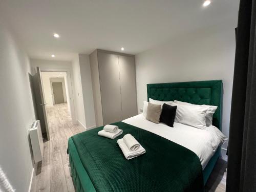 a bedroom with a green bed with two towels on it at Mustafa House By E2M Stays - 1 & 2 Bedroom Stunning Apt in Central Town in Camberley
