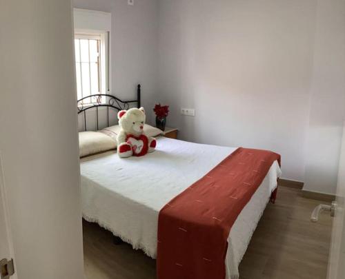 a teddy bear sitting on a bed in a bedroom at apartamento precioso y coqueto in Seville