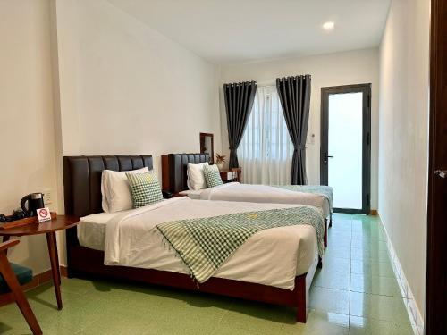1 dormitorio con 2 camas y mesa en Wildbird Hotel en Tràm Chim