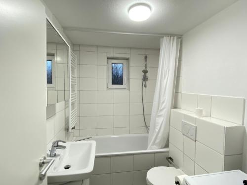 een witte badkamer met een bad en een wastafel bij LUXOMES: Design Apartment - private Parking - 4 People in Ingolstadt