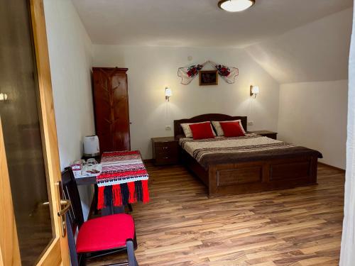 a bedroom with a bed with red pillows and a table at Casa Aurelia in Chişcău