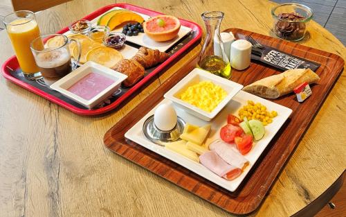 a table with two trays of breakfast foods and orange juice at ibis Genève Aéroport in Geneva