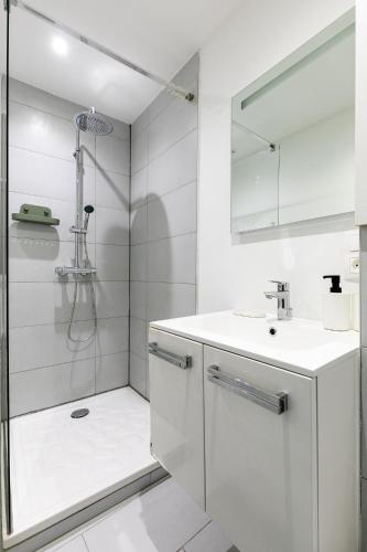 une salle de bain blanche avec une douche et un lavabo dans l'établissement Studio Cathédrale - Sainte-Madeleine, à Strasbourg