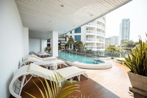 a balcony with white chairs and a swimming pool at Royal Beach View in Pattaya South