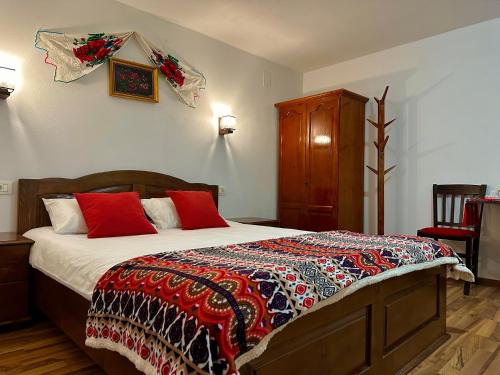 a bedroom with a large bed with red pillows at Casa Aurelia in Chişcău