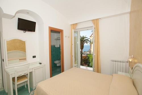 una camera con letto, lavandino e specchio di Hotel Villa Sirena - Thermae & SPA a Ischia