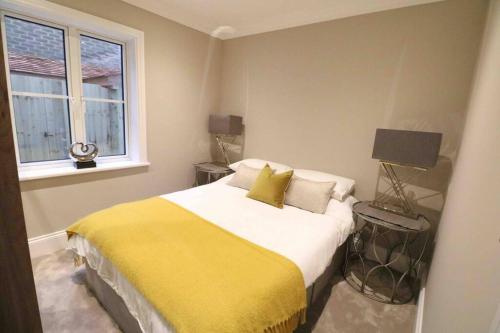 um quarto com uma cama com um cobertor amarelo e uma janela em Jubilee apartment, Winchester em Winchester