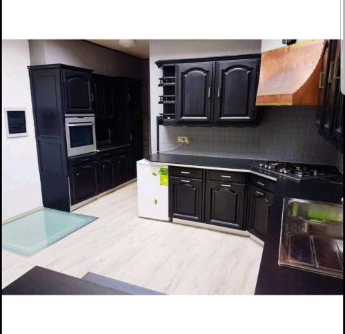 a kitchen with black cabinets and a wooden floor at Agréable chambre in Seraing