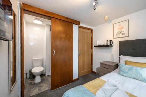 a bathroom with a bed and a toilet in a room at The New Lodge in Pontardawe