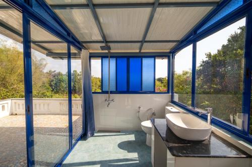 uma casa de banho com uma banheira, um lavatório e janelas em Gaia's Garden Guest House em Auroville