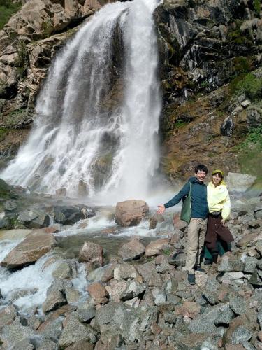 two people standing in front of a waterfall at Spring Family Guest House in Tersak