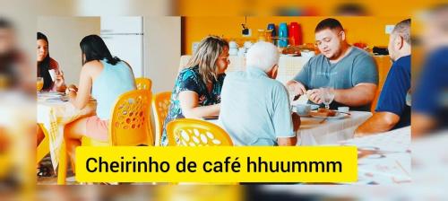 a group of people sitting around a table in a kitchen at Ecomar Pousada in São José da Coroa Grande