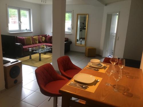 sala de estar con mesa de madera y sillas rojas en Diane‘s Ferienwohnung, en Meckesheim