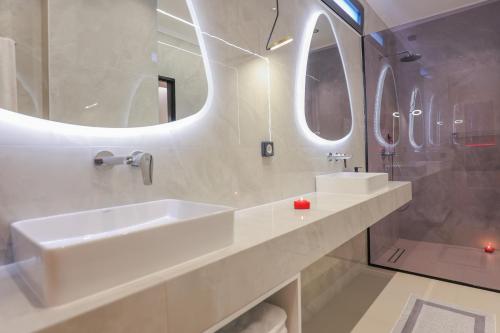 a white bathroom with two sinks and mirrors at City Compass Luxury Villa in Faliraki