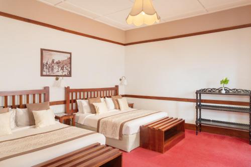 a hotel room with two beds and a red carpet at The Grand Hotel - Heritage Grand in Nuwara Eliya