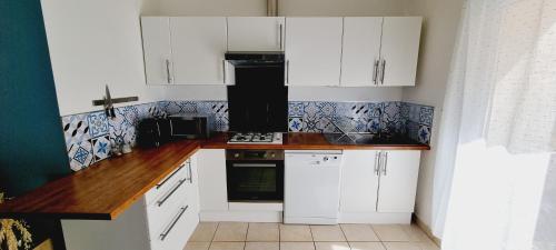 une cuisine avec des armoires blanches et un four à plaques de cuisson dans l'établissement Agréable appartement avec 2 places de parking dans le garage, à Béziers