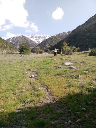two people walking in a field with mountains in the background at Spring Family Guest House in Tersak