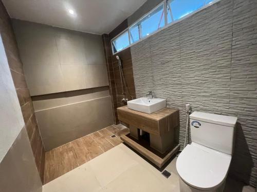 ein Badezimmer mit einem weißen WC und einem Waschbecken in der Unterkunft Kesa Cloud 9 Hotel & Resort Siargao in General Luna