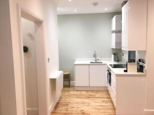 a kitchen with white cabinets and a wooden floor at No.1 The Old Printworks, Winchester in Winchester