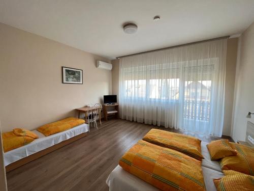 1 Schlafzimmer mit 2 Betten, einem Schreibtisch und einem Fenster in der Unterkunft Globus Guesthouse, Vendégház in Sormás