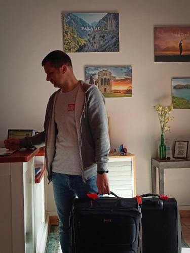 a man standing with a suitcase in a room at Hotel Rural Cuartamenteru in Llanes