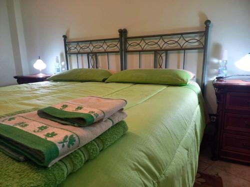 a large bed with green sheets and pillows on it at B&B Le Colonne in Montefusco