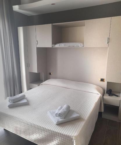 a bedroom with a white bed with towels on it at Hotel Royal Plaza in Rimini