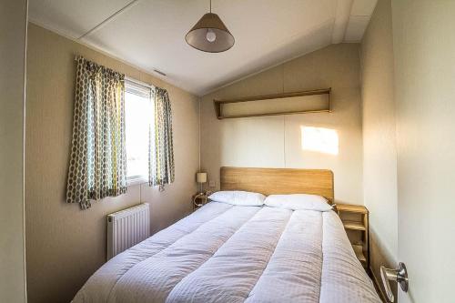 a bedroom with a large bed with a window at Caravan With Decking At Highfield Grange In Essex Ref 26452ba in Clacton-on-Sea