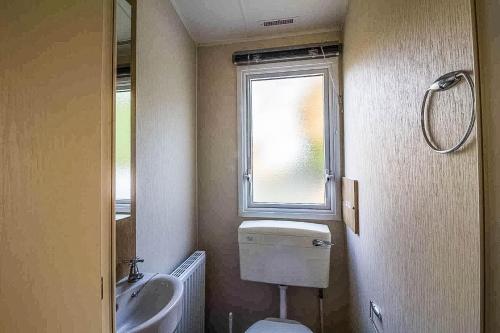 uma casa de banho com um WC, um lavatório e uma janela em Caravan With Decking At Highfield Grange In Essex Ref 26452ba em Clacton-on-Sea