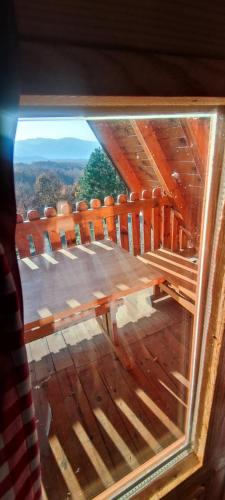 a view through a glass window of a wooden deck at Seoski Turizam Feniks - apartman Ostrog in Kosjerić