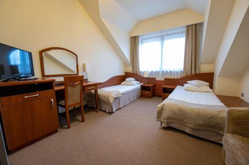 a hotel room with two beds and a mirror at Hotel Szelców in Lesko