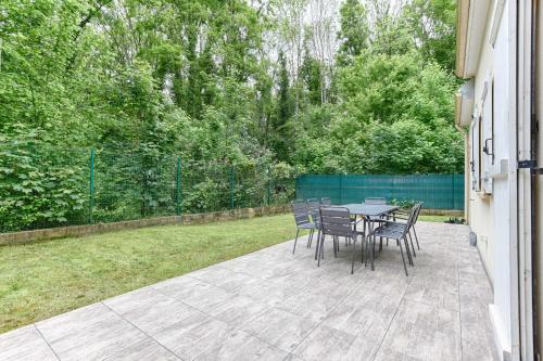 a patio with a table and chairs and a yard at Square-bnb - La Maison Pastèque à 8min de Disney in Montévrain