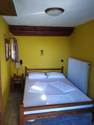 a bed in a room with a yellow wall at Double studio room in Mylopotamos in Tsagarada