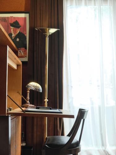 a desk with a lamp and a chair next to a window at Hôtel particulier Le DOGE - Relais & Châteaux in Casablanca