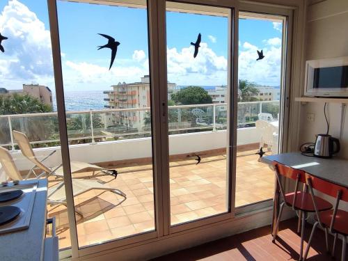 une cuisine avec un balcon avec des oiseaux qui volent dans le ciel dans l'établissement Appartement 2 chambres avec terrasse au Lavandou - FR-1-308-122, au Lavandou