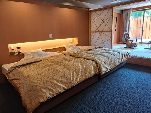ein Schlafzimmer mit einem großen Bett und einem Fenster in der Unterkunft Shiobara Onsen Ryokan Kamiaizuya in Nasushiobara