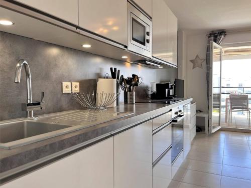 une cuisine avec un évier et un plan de travail dans l'établissement Charmant T2 climatisé avec grande terrasse, piscine et parking privatif, proche plage et commerces. - FR-1-251-441, au Lavandou