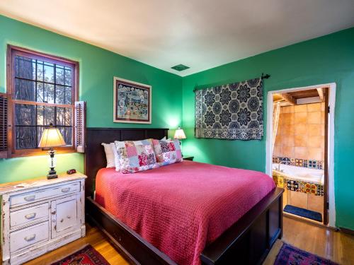 1 dormitorio con paredes verdes y 1 cama con colcha roja en La Vida Buena, 2 Bedrooms, Sleeps 4, Fireplace, Patio, Yard, Grill, en Santa Fe