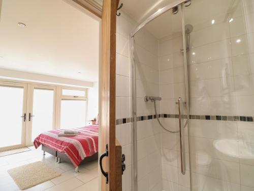 a bathroom with a shower and a bed in it at Malt Barn in Burford