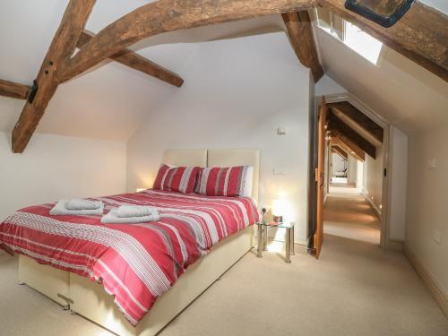 a bedroom with a bed with a red and white blanket at Malt Barn in Burford